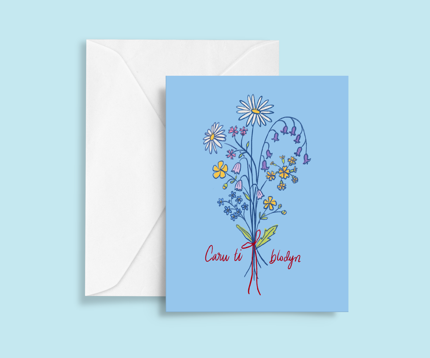 Romantic greeting card. Colour pencil drawing of bouquet of wild flowers tied with red bow. Daisy, buttercups, forget me nots, cowslips, harebells, red campion, bluebells, Handwritten text reads Caru ti blodyn, Welsh for Love you flower