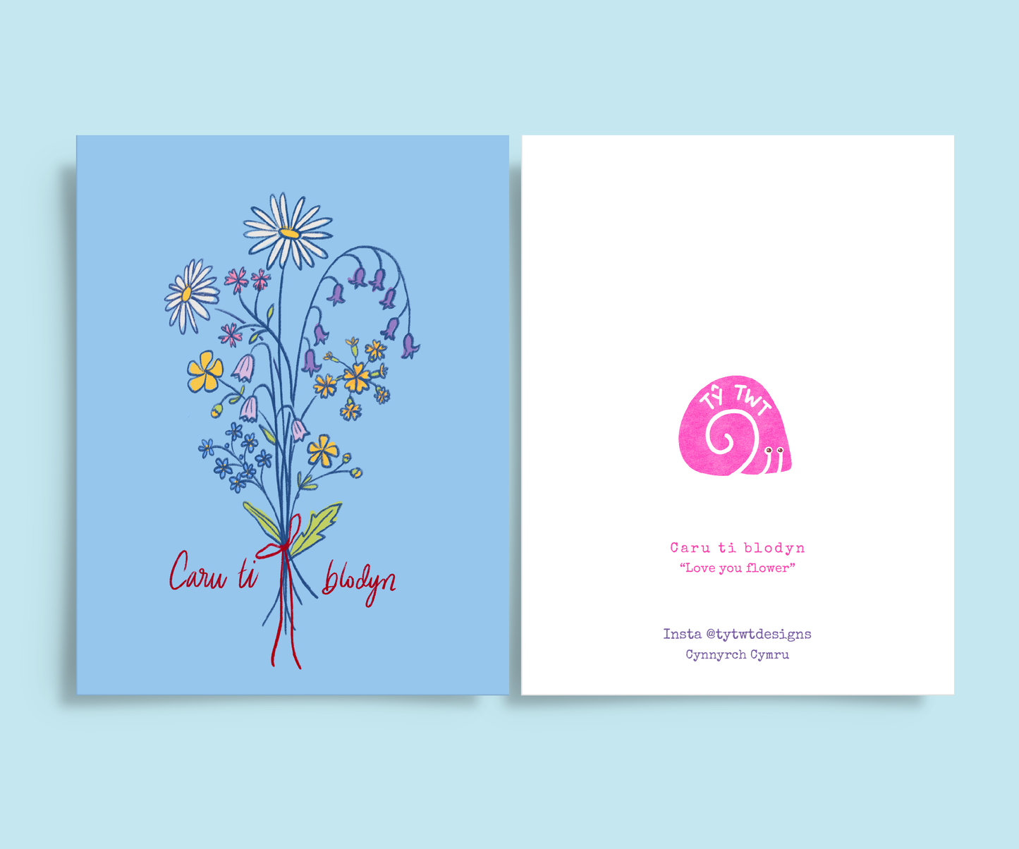 Front and back of greeting card. Right: Colour pencil drawing of bouquet of wild flowers tied with red bow. Daisy, buttercups, forget me nots, cowslips, barebells, red campion, bluebells, Handwritten text Caru ti blodyn. Left back @tytwtdesigns