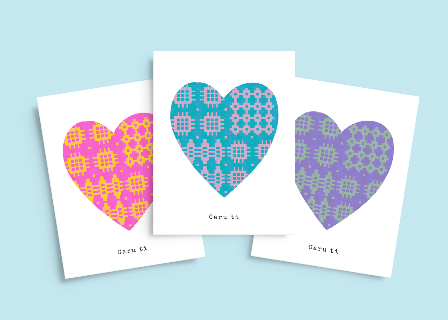 Set of three romatic cards in pink & yellow, purple & green, and blue & lilac, all featuring traditional blanket pattern hearts. Typewriter text below reads Caru ti, Welsh for Love you