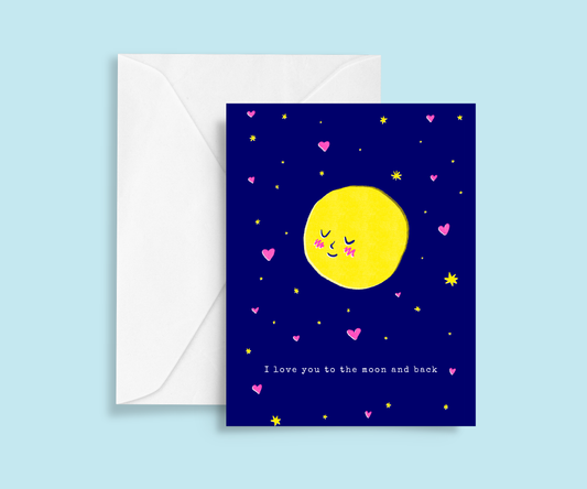 Blue background with envelope and romantic greeting card. On the dark blue card is risograph print of a blushing moon amongst stars and hearts, Typewriter text below reads I love you to the moon and back