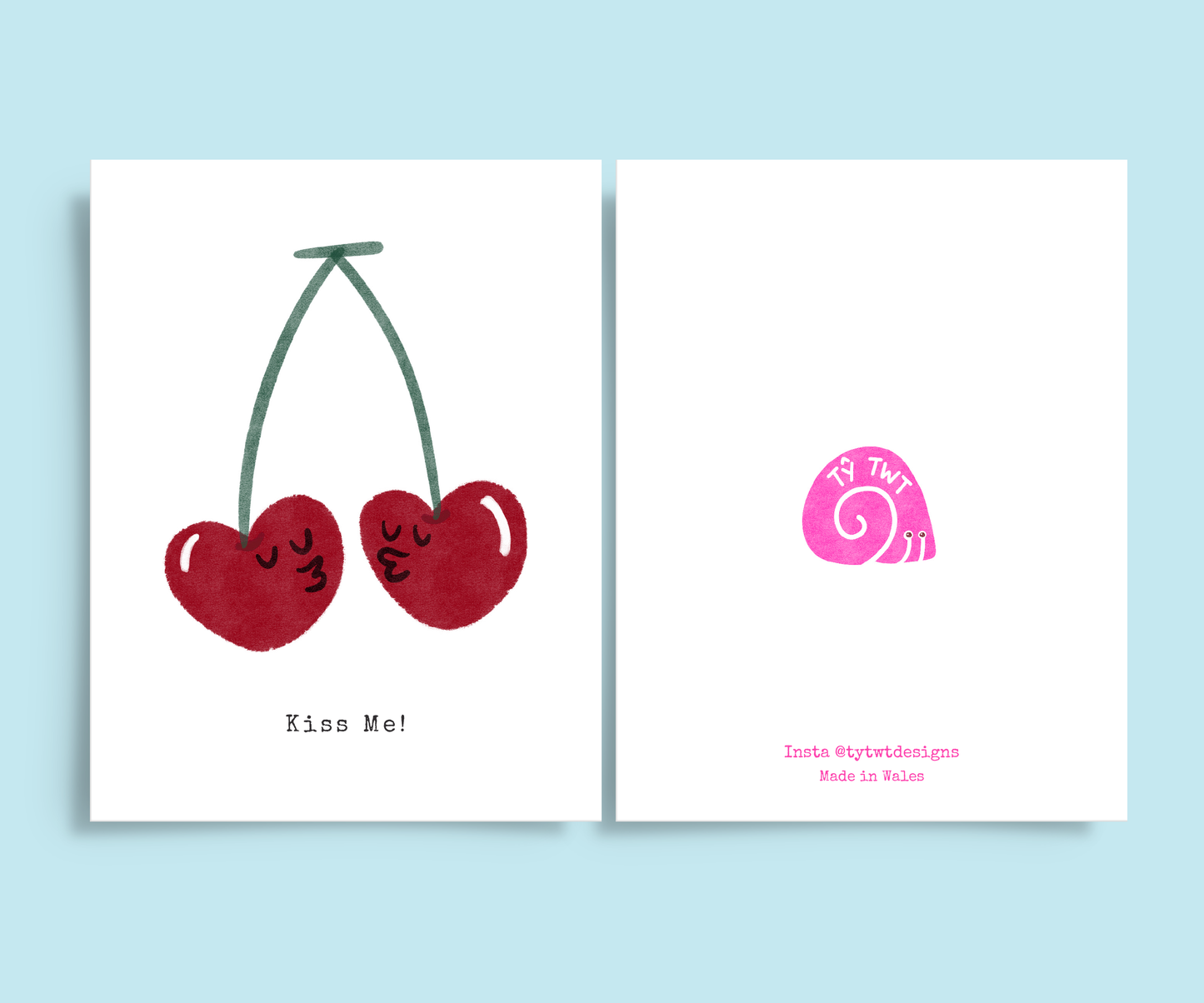 Both sides of romantic greeting card. Right is front of card with hand drawn print two cherries with faces kissing. Typewriter text below reads Kiss me. Left is back of card  @tytwtdesigns