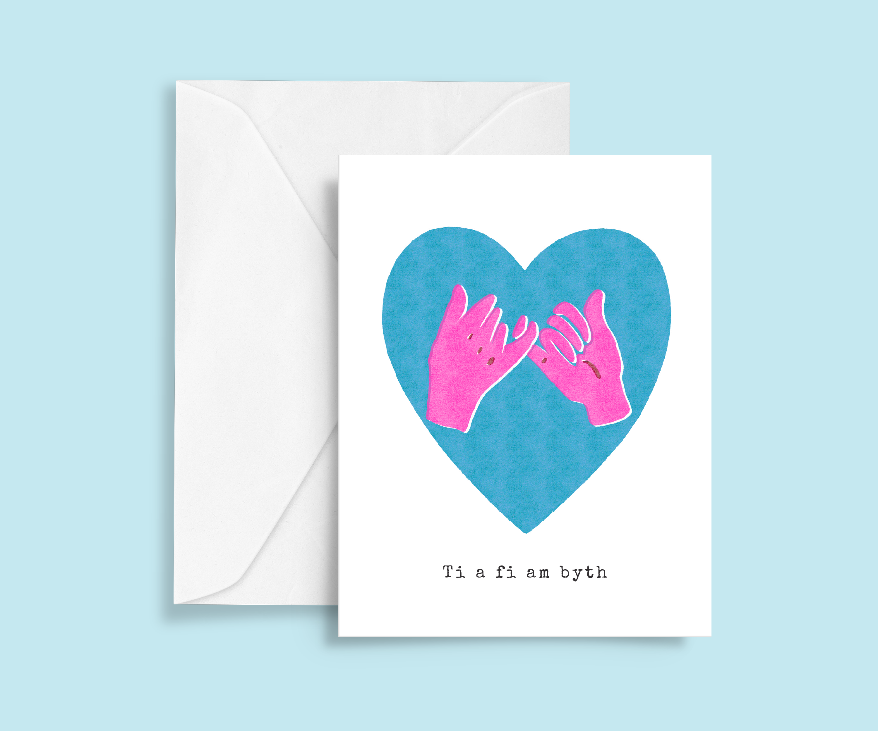 White A6 greeting card. Two bright pink hands pinky promise gesture inside vibrant blue heart shape. Off set risograph print. Typewriter text below says Ti a fi am byth